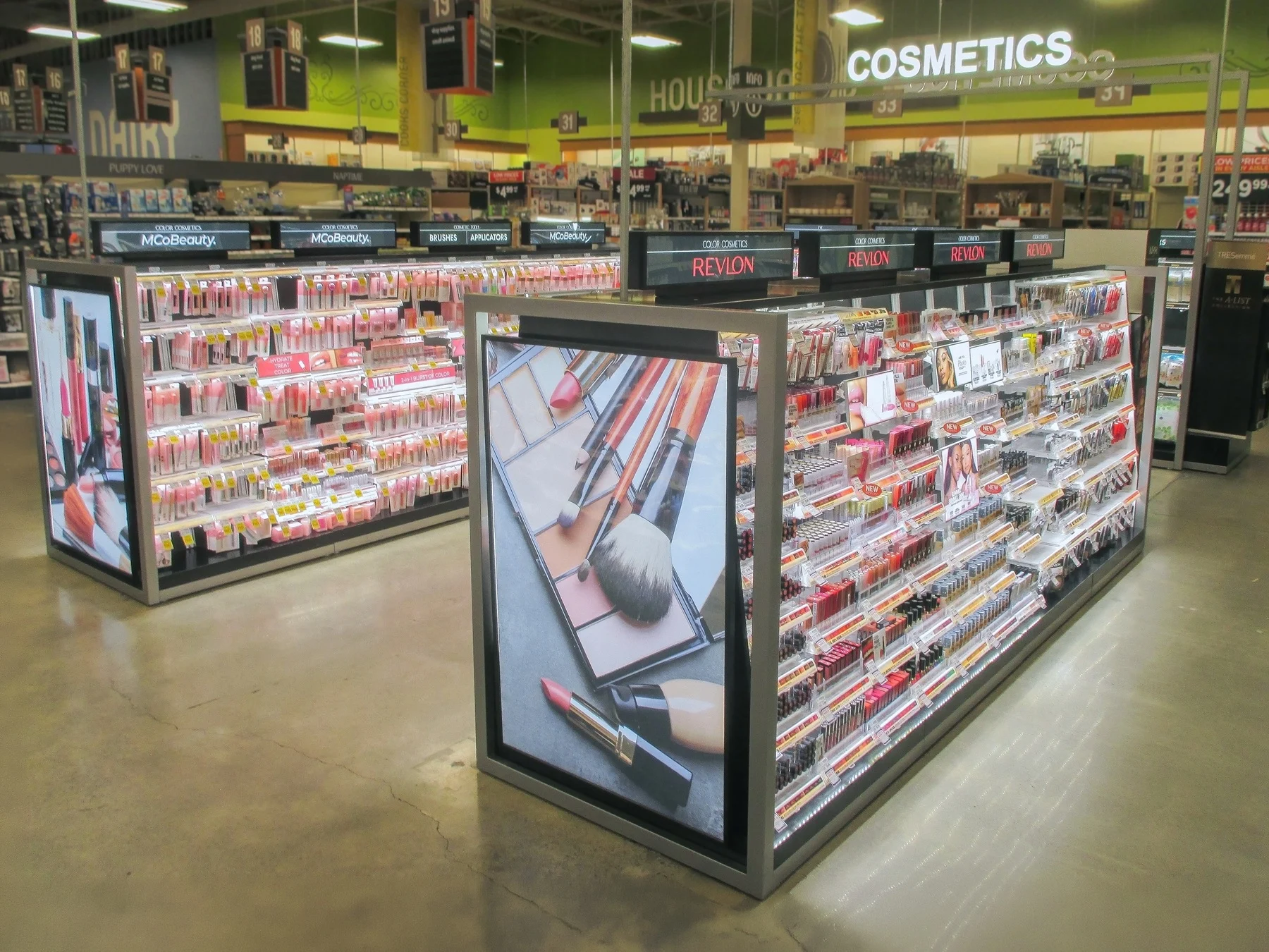 Lit PM Plastics cosmetics island display in a retail aisle